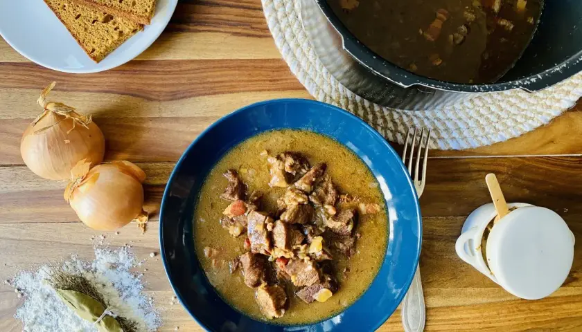 Carbonade flamande mijotée dans un Cookeo, servie dans un bol bleu avec du pain de seigle.