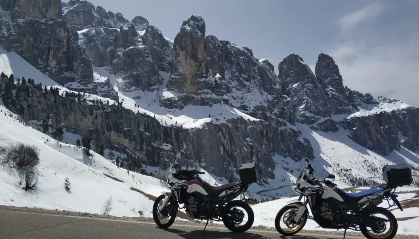 Due moto pronte per affrontare i passi bergamaschi innevati, con imponenti vette rocciose sullo sfondo.