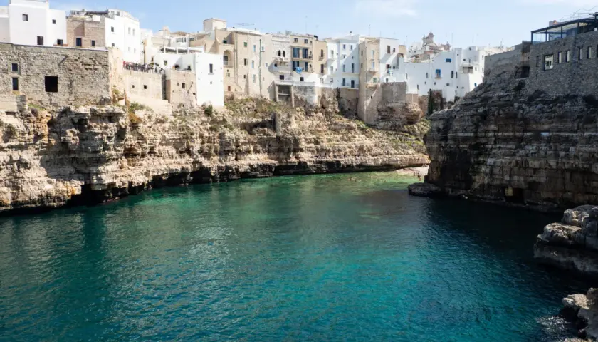 Un estany gento con aguas cristalinas rodea un pueblo blanco construido sobre acantilados rocosos.