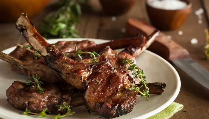 Délicieuses côtelettes d'agneau grillées, garnies de thym frais, prêtes à être dégustées.