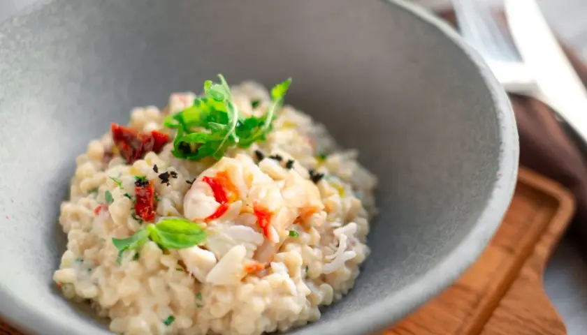 Un crémeux risotto aux fruits de mer, garni de basilic frais et de tomates séchées. Une recette de pâtes qui invite au voyage.