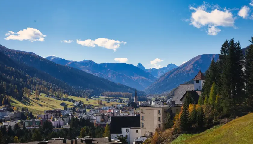 Widok na miasteczko w dolinie otoczonej górami. W oddali widać kościół z wieżą. Tak właśnie wygląda Davos.