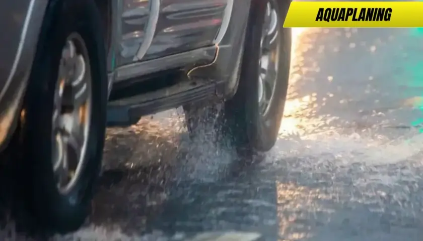 Un coche sufre aquaplaning en un día lluvioso, levantando agua al pasar.