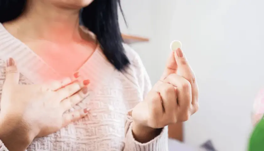Kobieta z pieczeniem w klatce piersiowej trzyma tabletkę, zastanawiając się: ipp co to za lek?