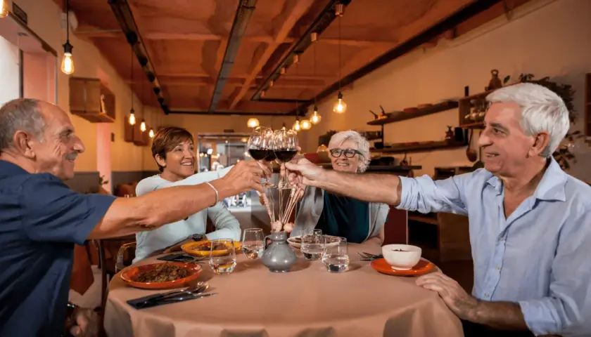 Cztery osoby wznoszą toast kieliszkami wina, tworząc radosny efekt cocktail party.