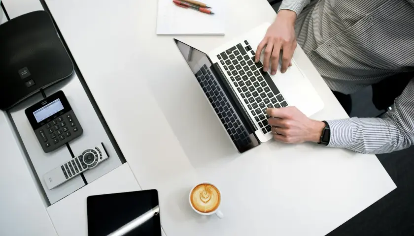 Kto to jest administrator? To osoba pracująca przy laptopie, z telefonem Cisco, tabletem i kawą.
