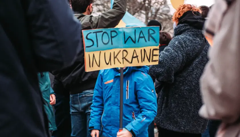 Kind hält Schild "Stop War in Ukraine". Ein starkes Bild, das an die Stimmen im Ukraine Podcast erinnert, die Frieden fordern.