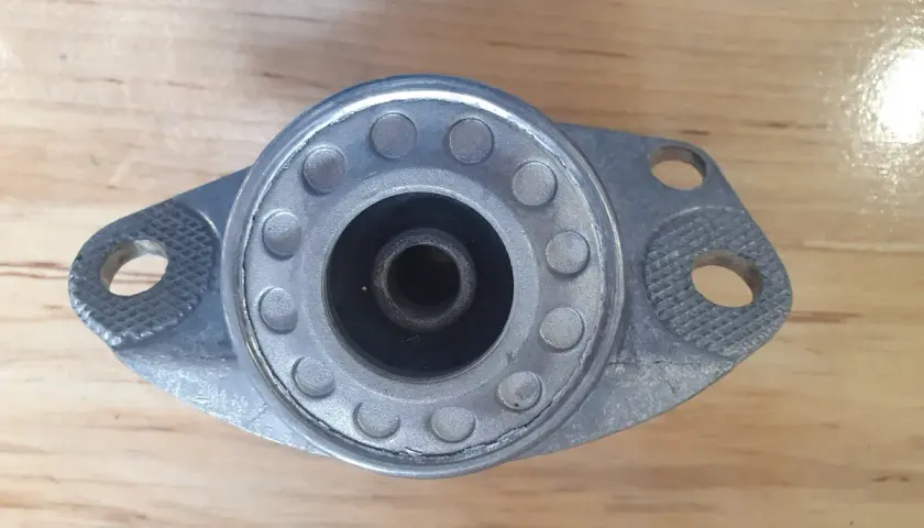 Metalowe górne mocowanie amortyzatora z gumowym elementem centrującym i otworami montażowymi.