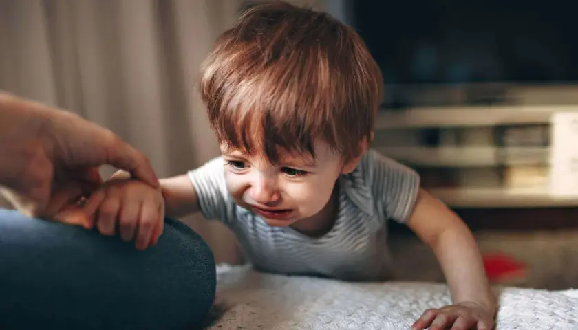 Gråtande bebis med rött hår, en high need baby som håller en vuxen hand.