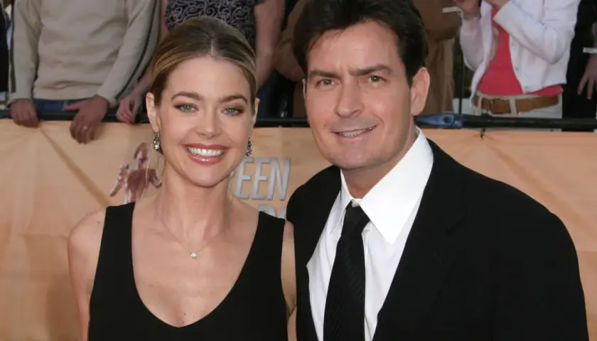 Charlie Sheen i jego żona, Denise Richards, uśmiechają się do aparatu na czerwonym dywanie.