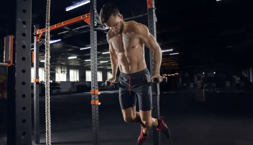 Mężczyzna wykonuje pompki na poręczach w siłowni CrossFit.