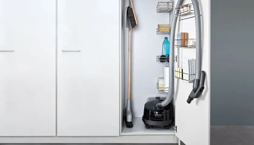 Solución de almacenamiento para aspiradora y escoba, con estantes para productos de limpieza.
