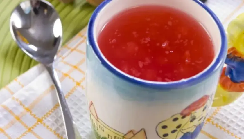 Czerwony kisiel na diecie w kubeczku z bajkowym wzorem, obok łyżeczka. Idealny na lekki deser.