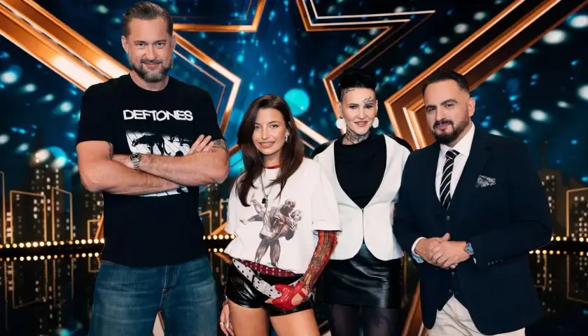 Jury mam talent 2026: mężczyzna w czarnej koszulce, młoda kobieta w białej bluzce, kobieta z tatuażami i mężczyzna w garniturze.