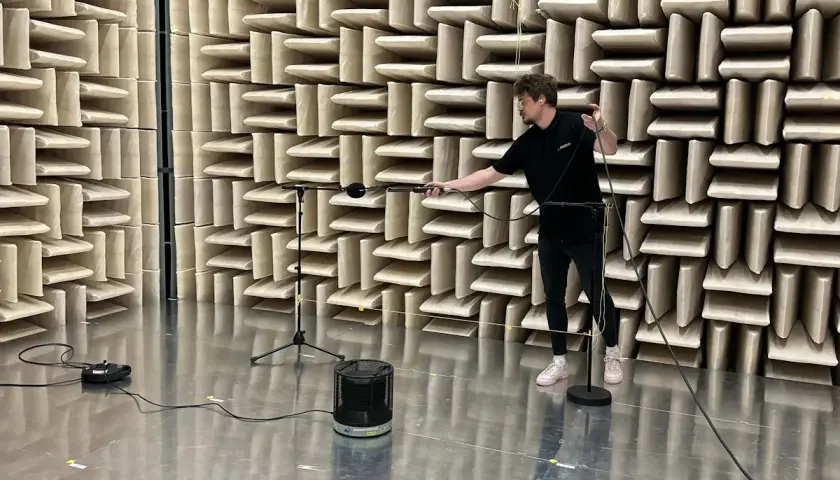 Hombre ajustando micrófonos en cámara anecoica para medir la unidad de potencia acústica de un altavoz.