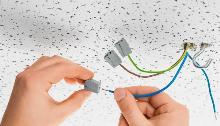 Ręce montują przewody do złączek elektrycznych. To szybkie i bezpieczne rozwiązanie, czy to wago czy kostka, ułatwia instalację.