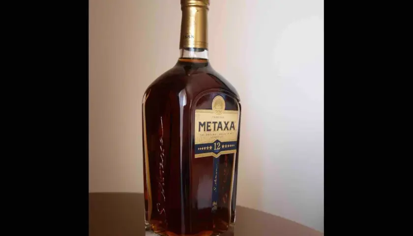 Butelka greckiego brandy Metaxa 12 gwiazdek na stole.