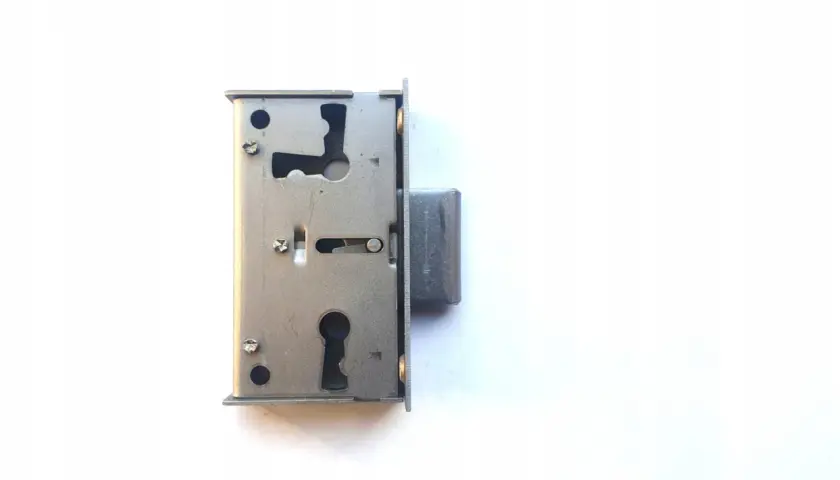 Metalowy zamek meblowy nakładany z otworem na klucz i mechanizmem zapadkowym, gotowy do montażu.