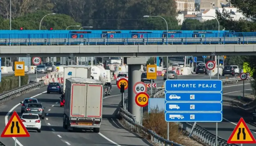 Tráfico lento en peaje con señales de límite de velocidad y de carril estrecho. Los vehículos esperan para pagar el importe del peaje.