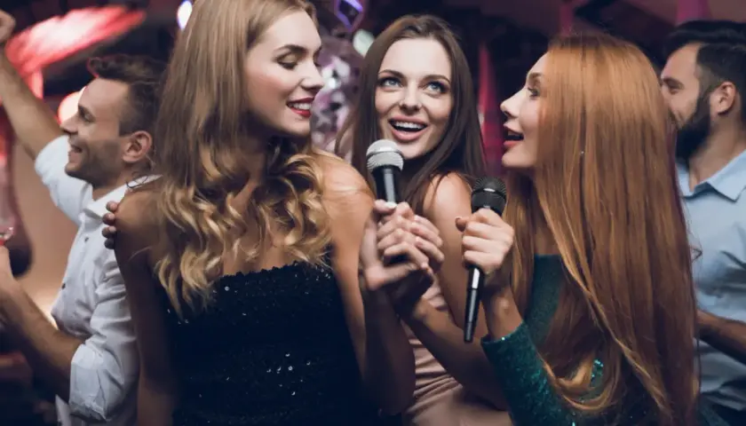 Trzy kobiety śpiewają do mikrofonów, bawiąc się przy fajnych piosenkach do śpiewania.