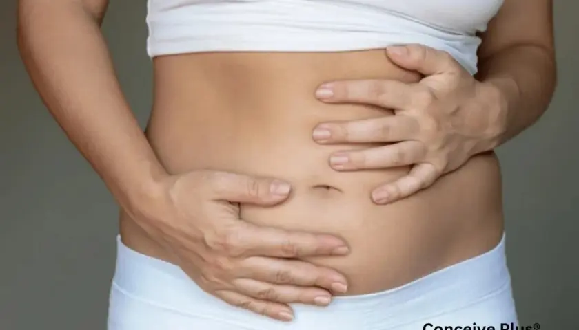 Manos acariciando suavemente una barriga de embarazada de 1 mes, con un ligero abultamiento que anuncia una nueva vida.