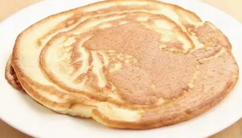 Ein goldbrauner Pfannkuchen ohne Ei auf einem weißen Teller, perfekt für ein leichtes Frühstück.