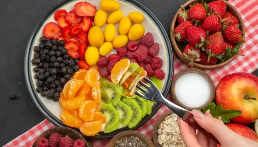 Kolorowa taca z owocami: truskawki, jagody, kumkwaty, maliny, mandarynki i kiwi. Idealna na śniadanie wspierające spalanie tłuszczu.