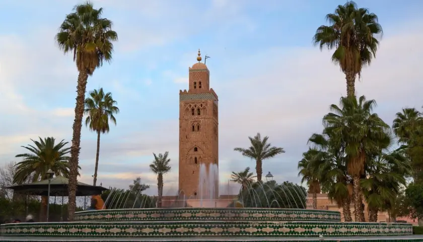 Torre Koutoubia y fuente en Marrakech, un lugar perfecto para tu visita de Marrakech en 3 días. Palmeras y cielo azul.