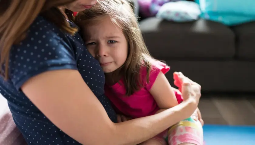 Smutna dziewczynka mocno przytula się do mamy. Widać jej łzy, co może świadczyć o lęku separacyjnym u 8 latka.
