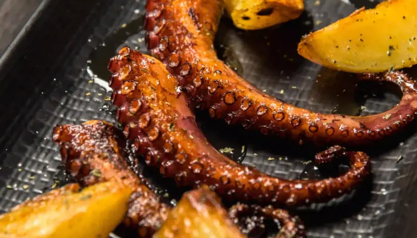 Tentacules de poulpe a la plancha, grillés à la perfection, servis avec des quartiers de pommes de terre dorées. Un délice croustillant et savoureux.