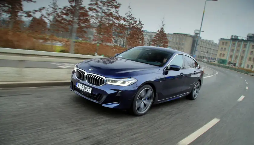 Granatowe BMW 640i sunie po miejskiej drodze, ukazując swoje eleganckie linie i sportowy charakter.