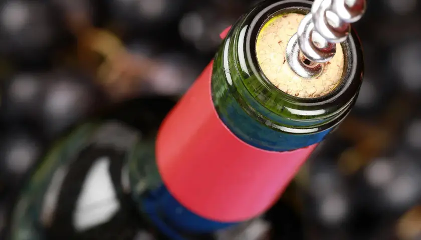 Ein Korkenzieher öffnet eine Flasche Wein, bereit für den Genuss. Ein Glas Wein am Tag hält den Arzt fern.