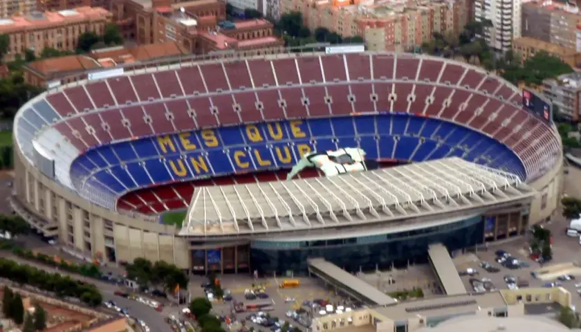 Camp Nou, z imponującą pojemnością, wita kibiców. Na trybunach widnieje napis "Més que un club".