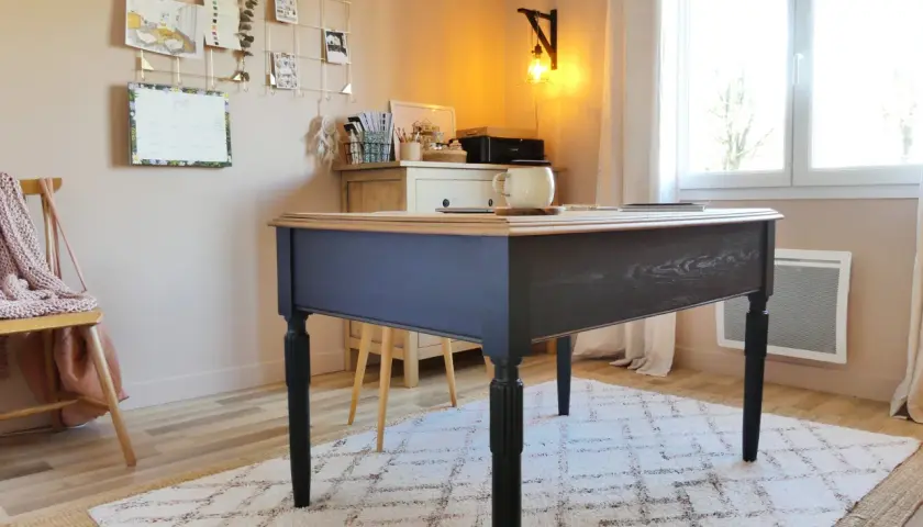 Bureau en bois peint en bleu marine, avec un plateau en bois naturel. Une tasse est posée sur le bureau.