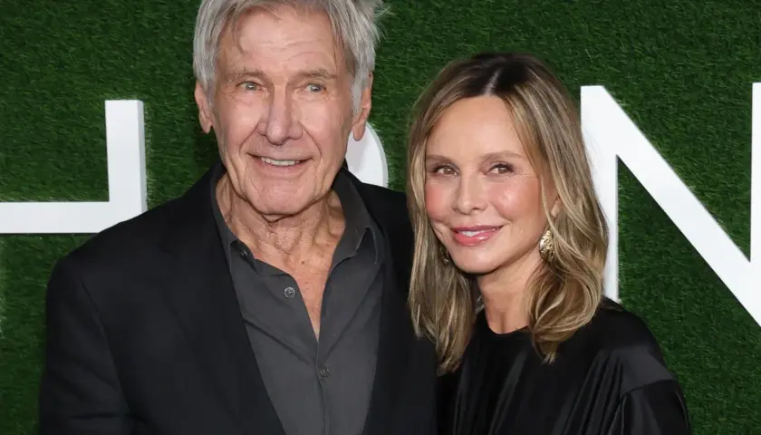 Harrison Ford z żoną Calistą Flockhart na tle zielonej ściany z białymi literami.