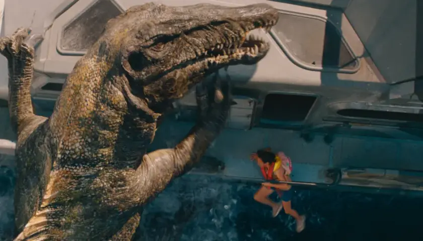 En enorm dinosaurie klättrar upp på en farkost i det nya Jurassic Park, med en liten flicka hängande vid räcket.
