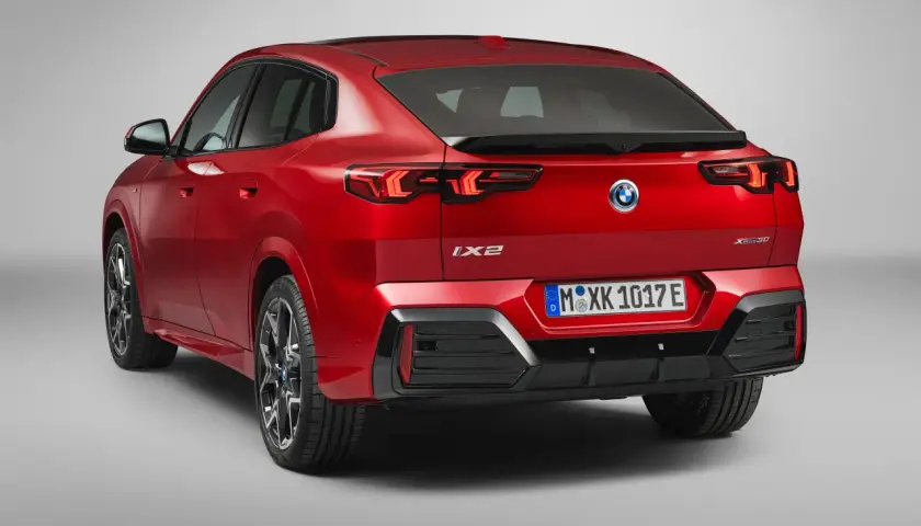 Czerwone BMW iX2 z napisem "XDrive30" na klapie bagażnika, z tyłu widoczne są lampy LED i tablica rejestracyjna.