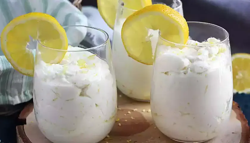 Trois verres de mousse au citron sans cuisson, décorés de rondelles de citron et de zeste. Un dessert frais et léger.