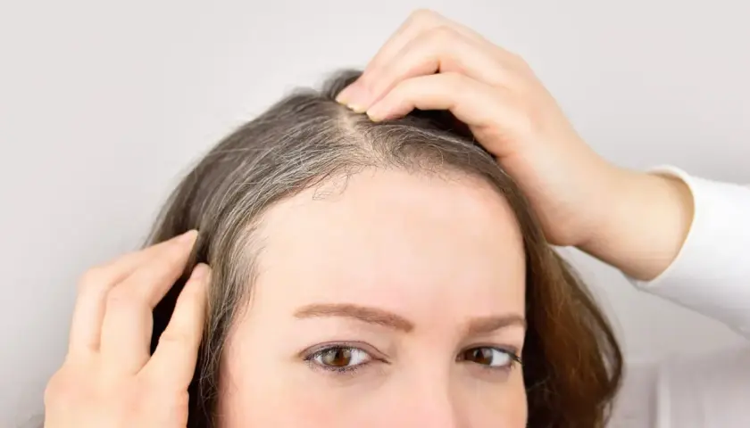 Mujer revisando sus canas, pensando en un baño de color para canas.