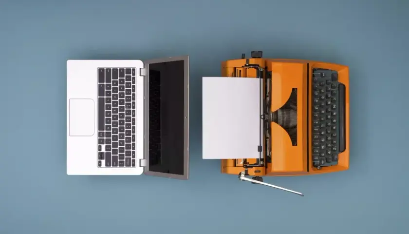 Un portátil y una máquina de escribir naranja con papel, ilustrando como se digitaliza un documento.