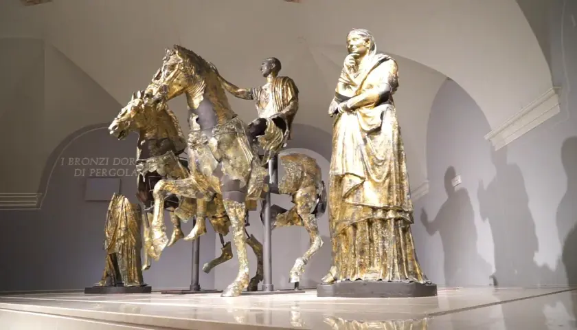 Bronzi dorati di Pergola: un cavaliere su un cavallo, una figura femminile e altre statue antiche.