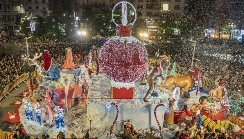 Desfile navideño en Santander con un gran adorno de bola de Navidad y figuras, rodeado de gente y confeti. Encendido luces Santander.
