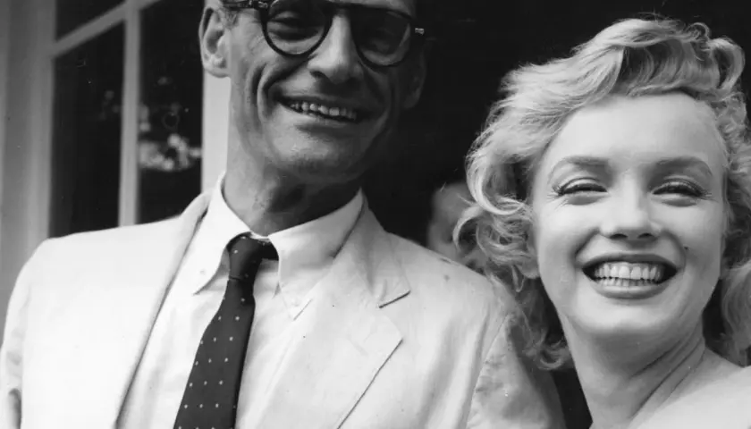 Marilyn Monroe i jej mąż Arthur Miller uśmiechają się radośnie do zdjęcia.