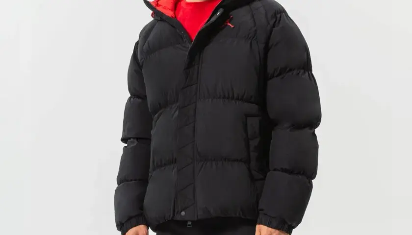 Mężczyzna w czarnej, puchowej kurtce Jordan Essentials z czerwonym wykończeniem i logo Jumpman.
