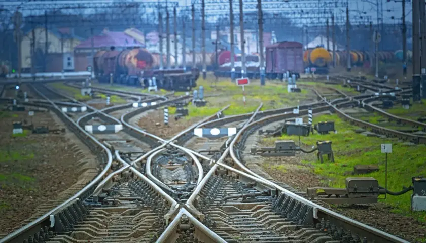 Skomplikowany węzeł torów kolejowych z widocznym wskaźnikiem W15. W tle stoją wagony towarowe.