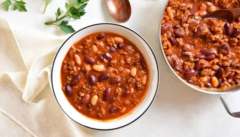 Aromaticzna zupa meksykańska z kurczakiem, pełna fasoli i mielonego mięsa, podana w misce i garnku.