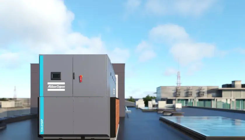 Enfriadora de aire-agua Atlas Copco TCA-215AP en una azotea, con edificios y cielo azul al fondo.