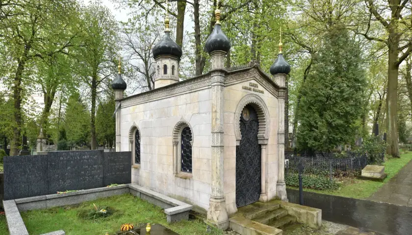 Imponujący grobowiec na cmentarzu, przypominający małą cerkiew, z charakterystycznymi kopułami i bogato zdobionymi drzwiami.