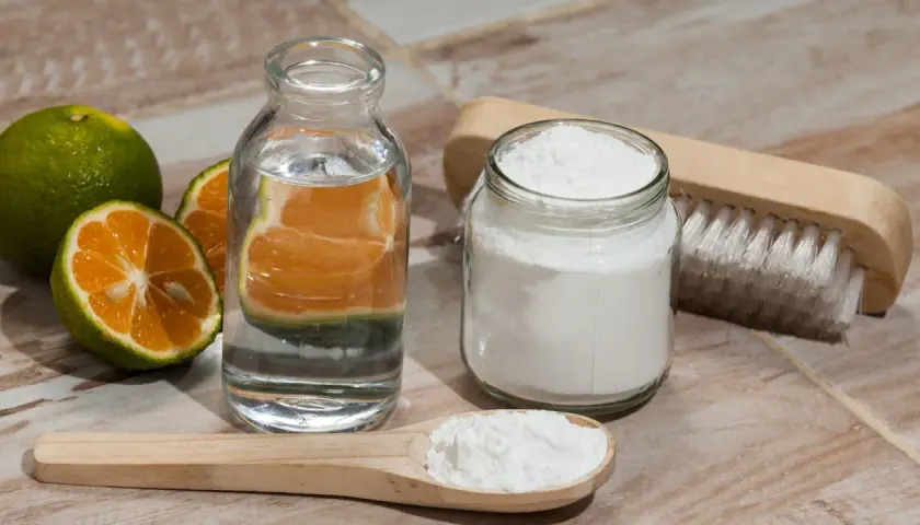 Ingrédients pour nettoyer manteau bicarbonate : citrons verts, eau, bicarbonate de soude et une brosse.