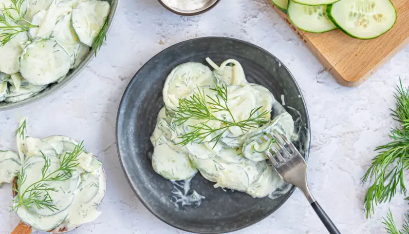 Cremiger Gurkensalat mit Schmand und frischem Dill, garniert mit Dillzweigen. Ein erfrischender Genuss!